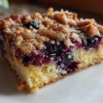 Close-up of a moist square slice of Easy Sheet Pan Blueberry Streusel Pancake with juicy berries and crumb topping.