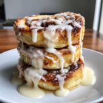 A tall stack of three fluffy Cinnamon Roll Pancakes topped with thick, dripping cream cheese icing.