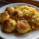Close-up of pan-fried German Dumplings With Buttered Cabbage served on a white plate.