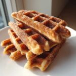 A close-up stack of crispy Gluten-Free Cinnamon Sugar Waffle Sticks coated heavily in sparkling sugar.