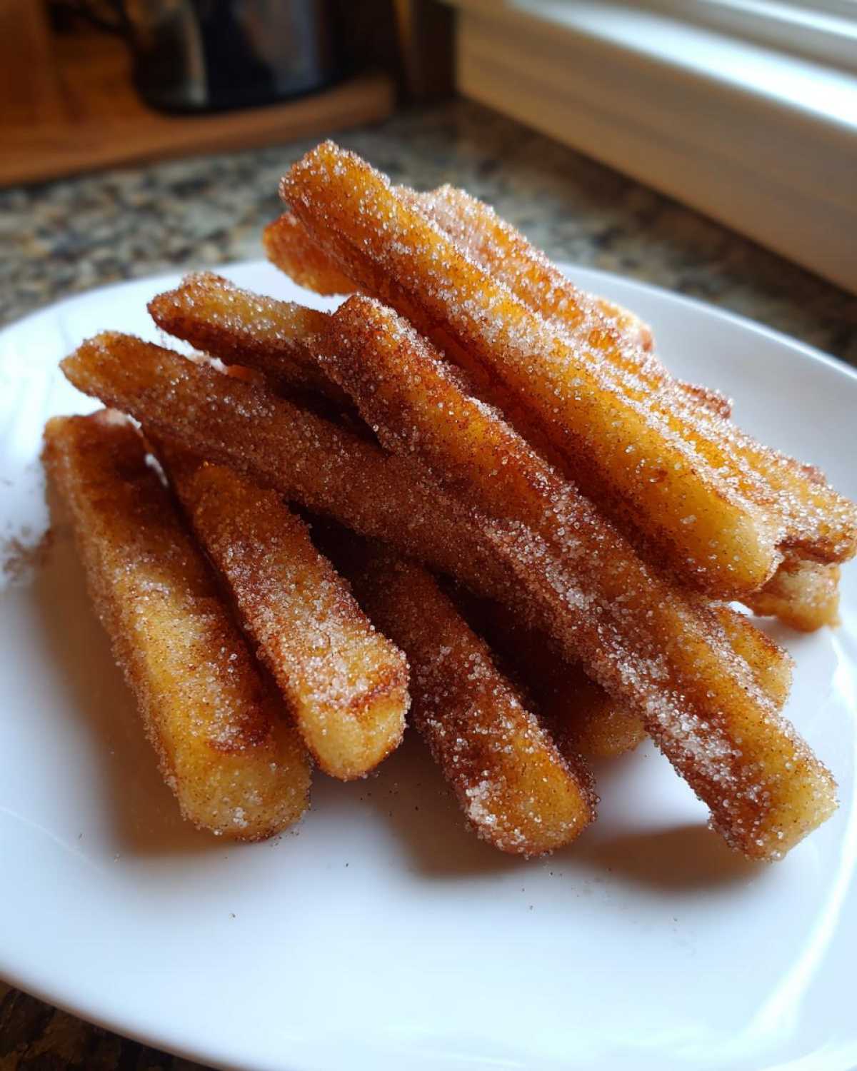 A close-up of stacked Gluten-Free Cinnamon Sugar Waffle Sticks heavily coated in sparkling cinnamon sugar.