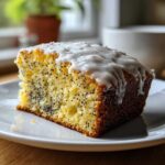 A close-up of a moist slice of Gluten-Free Lemon Almond Poppy Seed Cake topped with white lemon glaze.