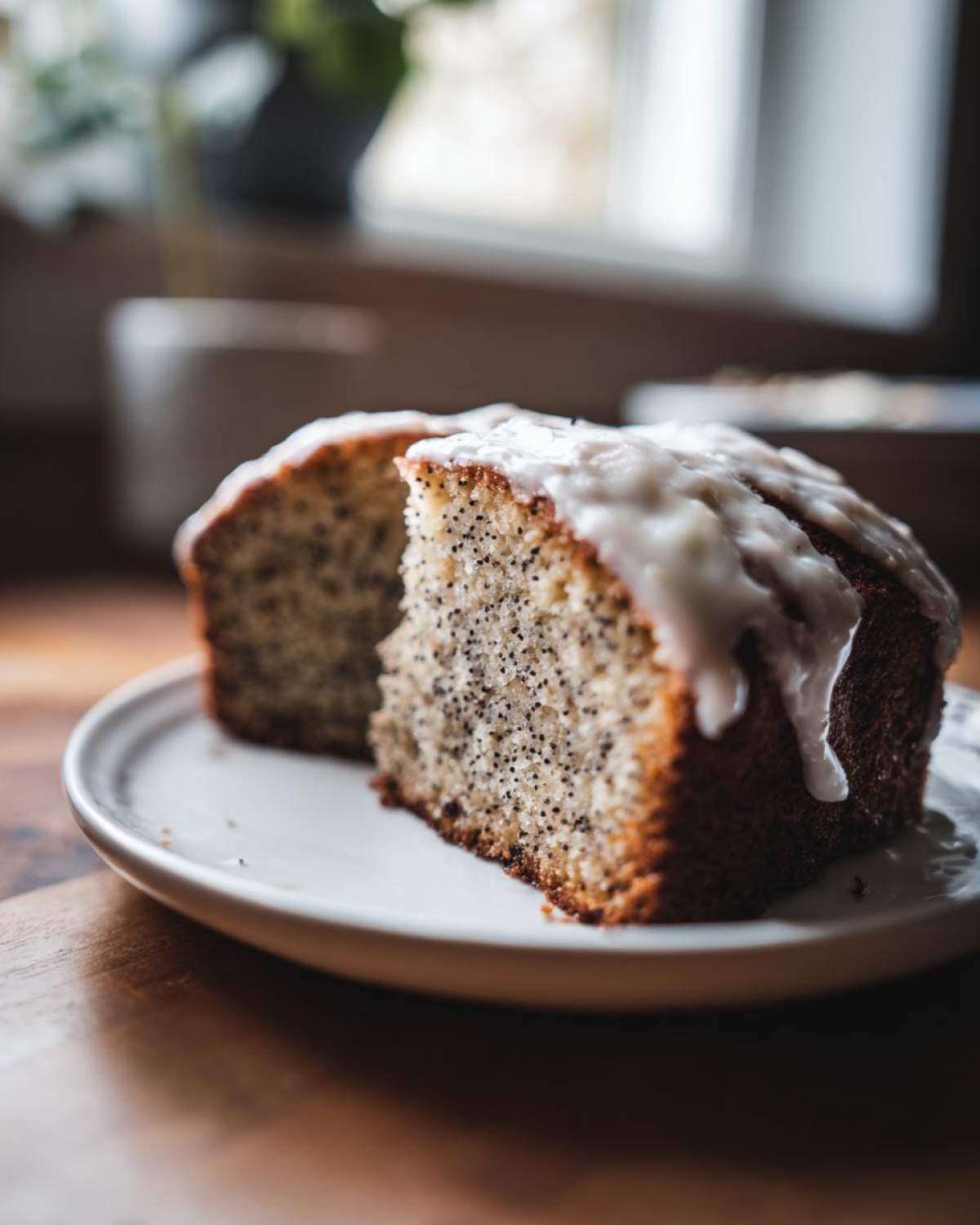 Two slices of moist Gluten-Free Lemon Almond Poppy Seed Cake topped with a thick white lemon glaze, served on a white plate.