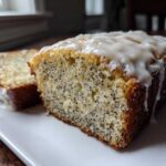 Close-up of two slices of moist Gluten-Free Lemon Almond Poppy Seed Cake topped with a thick lemon glaze.