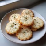 A small stack of golden Gluten-Free Lemon Thyme Shortbread Cookies garnished with fresh thyme sprigs on a light plate.