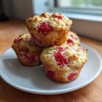 A stack of four freshly baked Gluten-Free Strawberry Oat Muffins with visible strawberry pieces, resting on a white plate.