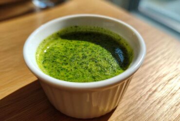 Close-up of vibrant Green Goddess Salad Dressing, freshly blended, served in a small white ramekin on a wooden table.