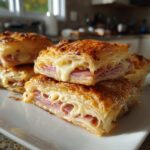 Close-up of golden Ham Cheese Puff Pastry Stacks cut in half showing layers of flaky pastry, ham, and gooey melted cheese.