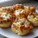 A plate of freshly baked, golden-brown High-Protein Cottage Cheese Bagel Bites topped with poppy seeds.