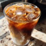 Close-up of Iced Brown Sugar Cinnamon Cold Brew layered with milk and filled with ice cubes, showing condensation.