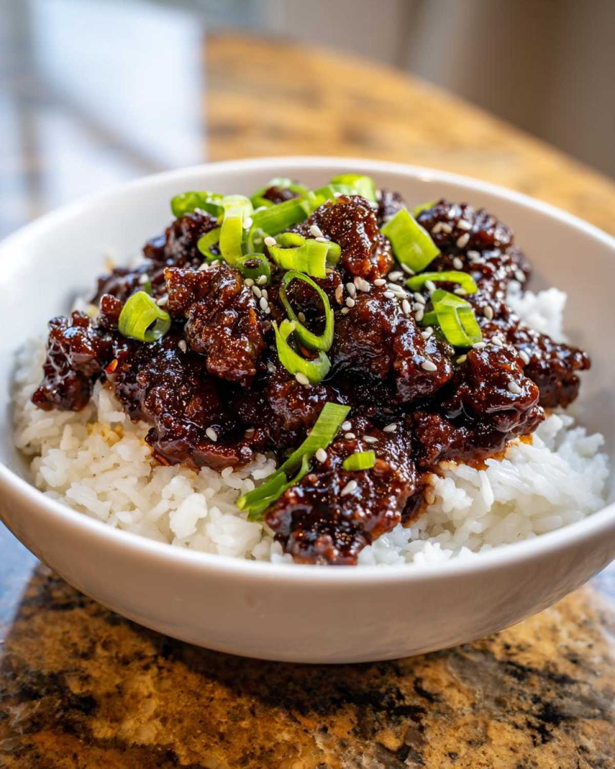 Close-up of Instant Pot Korean Beef and Rice Bowls, featuring saucy beef over white rice, topped with green onions and sesame seeds.