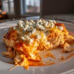 A close-up serving of Keto Creamy Buffalo Chicken Casserole topped with melted cheese and blue cheese crumbles.