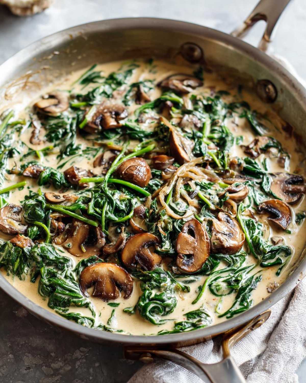 Close-up of Keto Creamy Spinach Mushroom Skillet cooking in a stainless steel pan with rich cream sauce.