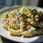 Close-up of Mexican Street Corn Pasta Salad featuring fusilli pasta, creamy sauce, corn kernels, red onion, and cilantro.