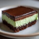 A close-up of a single serving of No-Bake Chocolate Mint Icebox Bars with chocolate crust, mint layer, and ganache topping.