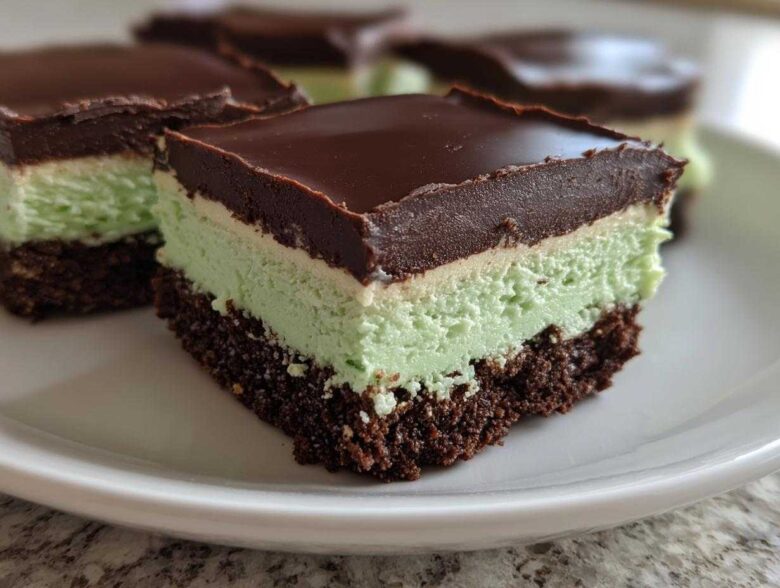 A close-up of a square No-Bake Chocolate Mint Icebox Bars slice showing chocolate crust, mint filling, and chocolate ganache topping.
