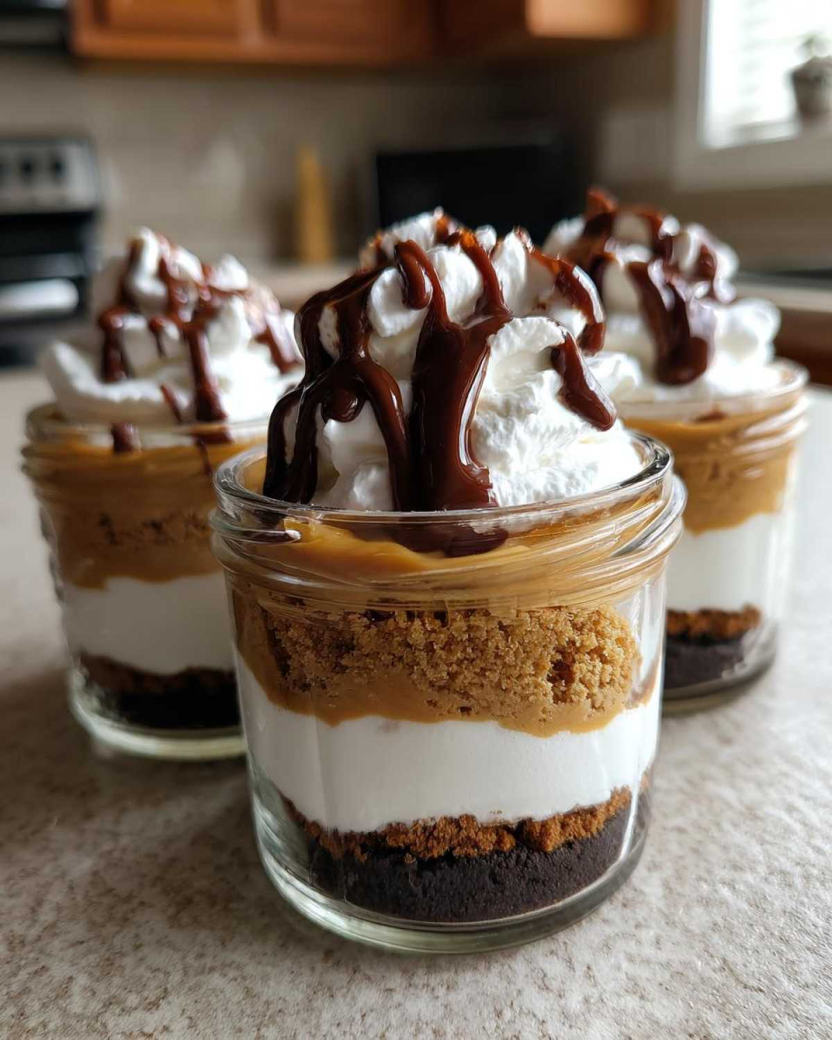 Three layered No-Bake Chocolate Peanut Butter Pie Jars topped with whipped cream and chocolate drizzle.