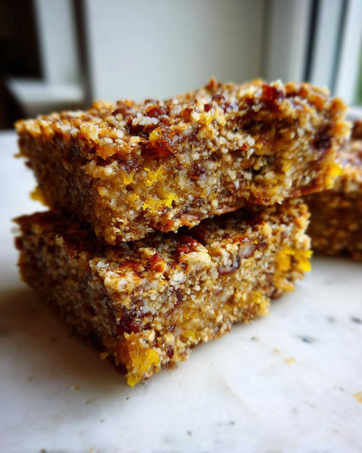Close-up of two stacked No-Bake Lemon Almond Date Bars showing the textured, chewy interior with visible almond and date pieces.
