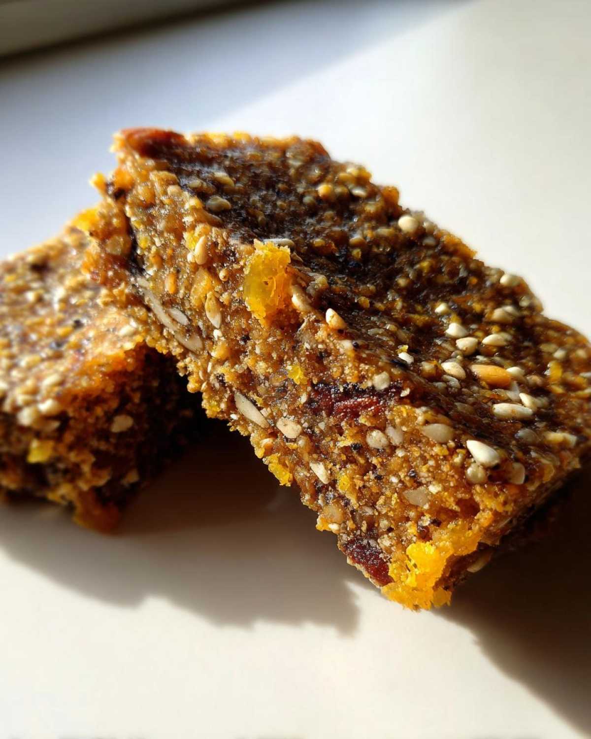 Close-up texture shot of two No-Bake Lemon Almond Date Bars showing visible seeds and dried fruit pieces.