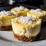 Four individual No-Bake Lemon Coconut Cheesecake Cups topped with shredded coconut on a white plate.