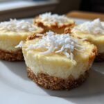 Four individual No-Bake Lemon Coconut Cheesecake Cups topped with shredded coconut on a white plate.