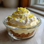 Close-up of a single serving No-Bake Lemon Cream Pie Cups in a glass dish with whipped cream and zest.