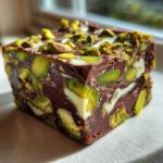 A single square of rich No-Bake Pistachio Chocolate Fudge Squares packed with bright green pistachios and white chocolate swirls.