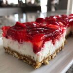 A close-up, cross-section view of a slice of No-Bake Strawberry Pretzel Dessert Bars showing the pretzel crust, cream cheese layer, and strawberry topping.