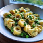 Close-up of One-Pot Creamy Garlic Butter Tortellini and Peas coated in a rich sauce and garnished with black pepper.