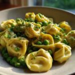 Close-up of One-Pot Creamy Garlic Butter Tortellini and Peas served in a light-colored bowl, garnished with herbs.