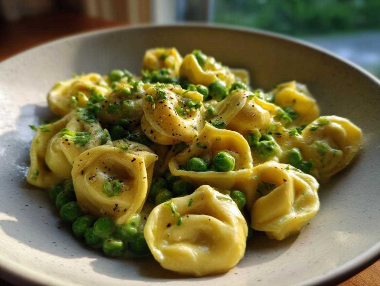 Close-up of One-Pot Creamy Garlic Butter Tortellini and Peas served in a light-colored bowl, garnished with herbs.