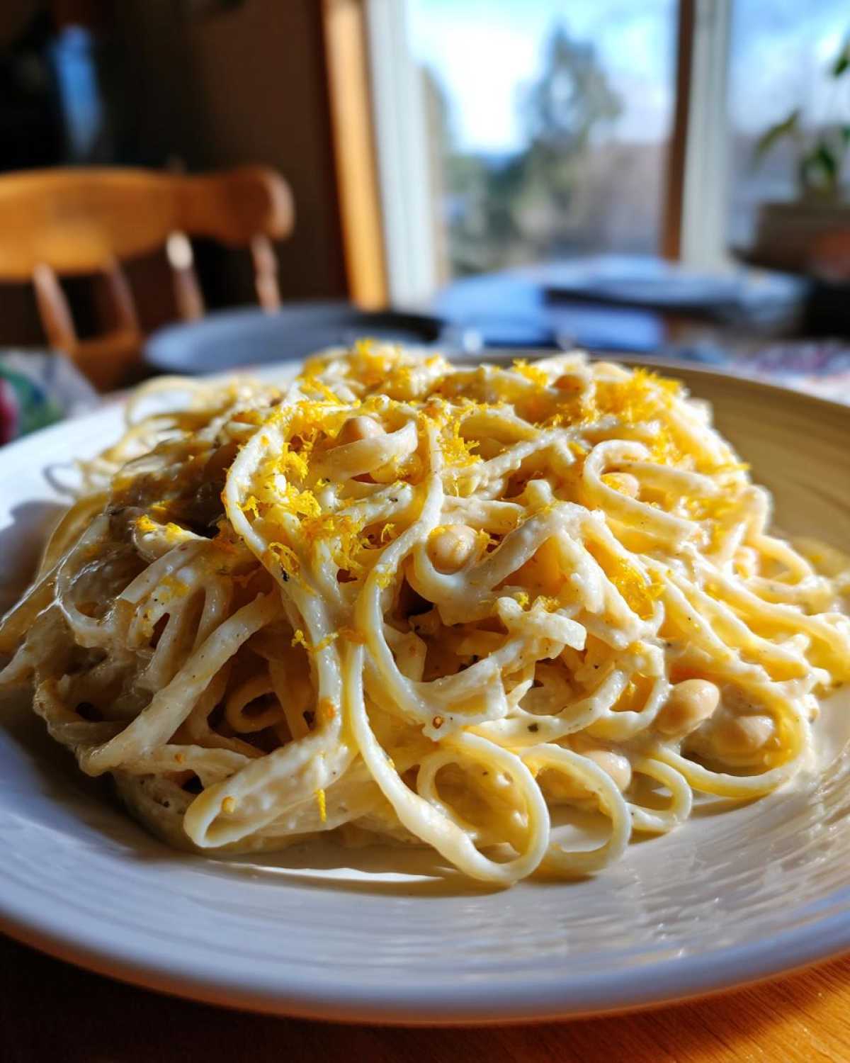 A serving of One-Pot Creamy White Bean Lemon Pasta topped with bright yellow lemon zest.