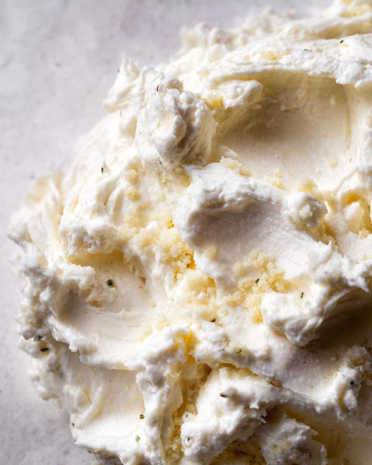 Macro shot showing the thick, whipped texture of a homemade cream sauce, possibly containing cheese or herbs.