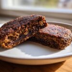Close-up of a perfectly seared black bean burger patty cut in half, showing the dark, textured interior.