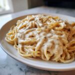 Close-up of spaghetti generously coated in creamy Easy Cottage Cheese Alfredo Sauce and black pepper.