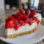 Close-up of a perfect slice of Strawberry Cream Pie showing the graham cracker crust, white cream filling, and glossy strawberry topping.
