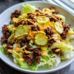 A close-up of a delicious big mac salad featuring lettuce, seasoned ground beef, shredded cheese, pickles, and special sauce.
