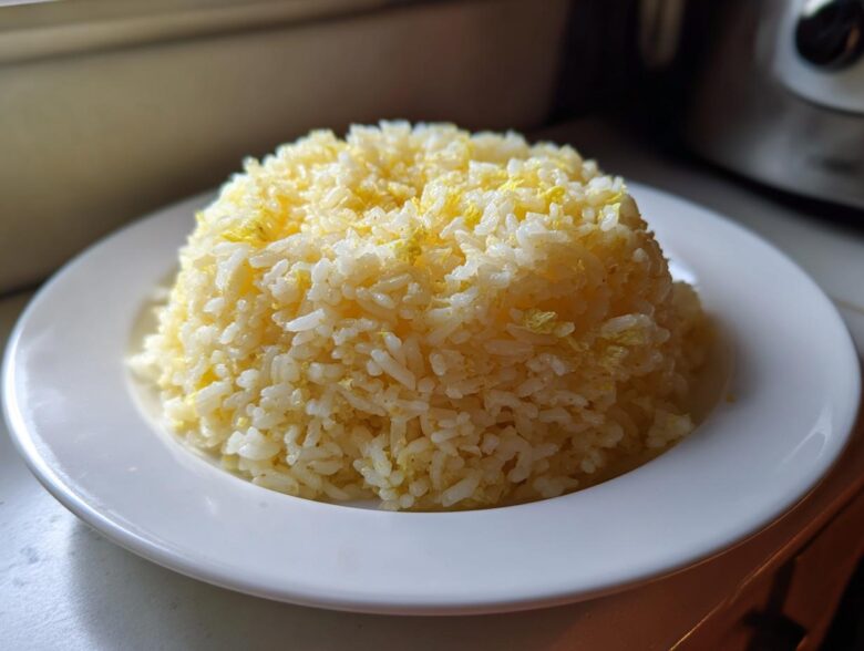 A perfectly molded serving of fluffy Texas Roadhouse Seasoned Rice with visible yellow flecks, served on a white plate.