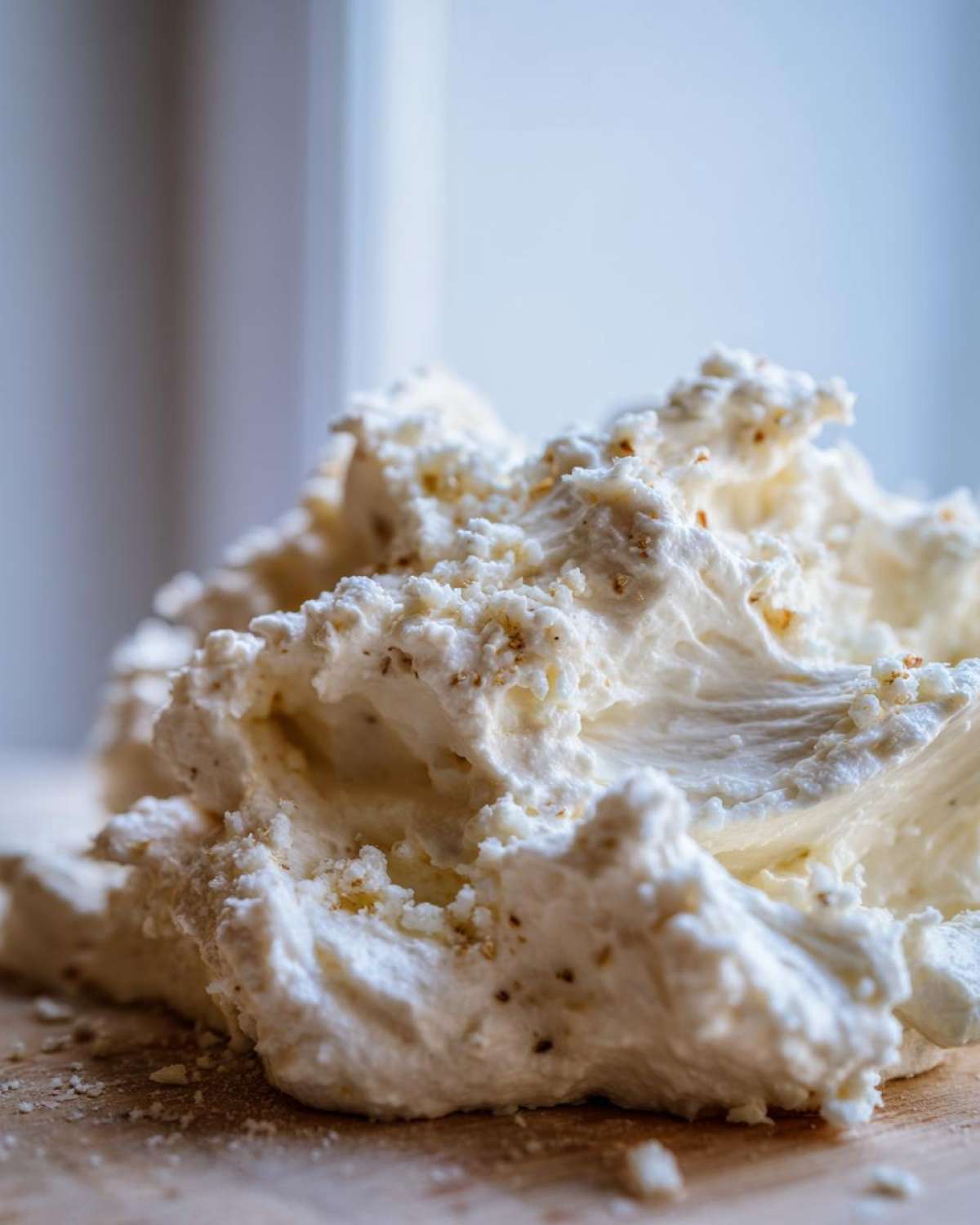 Close-up of a mound of thick, white, whipped cream sauce base with visible specks of seasoning.