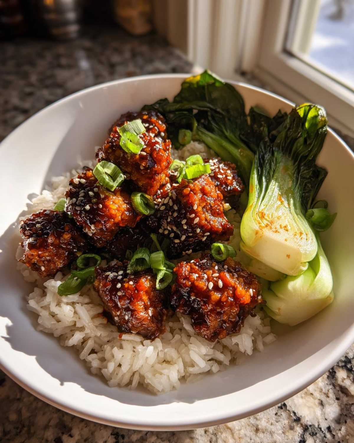 Close-up of a Vegan Crispy Sesame Tempeh Bowl featuring glazed tempeh pieces over white rice with bok choy.