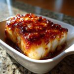A thick fillet of flaky white cod topped with a thick, glistening, reddish-brown honey garlic sauce.