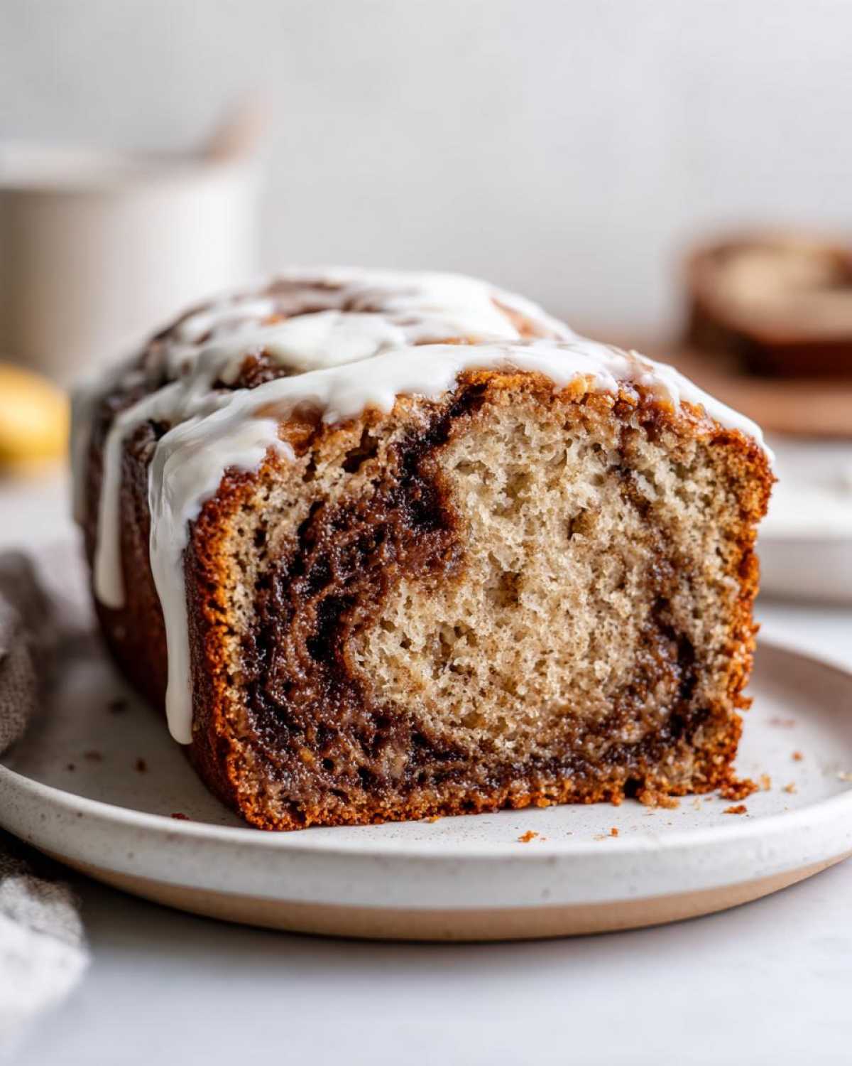 Cross-section view of a slice of Cinnamon Roll Banana Bread Loaf showing the swirl and white glaze.