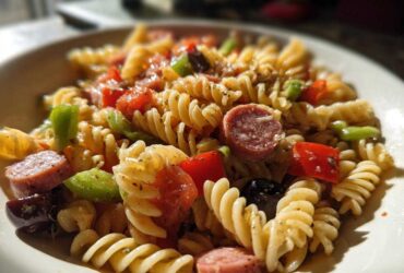 A close-up shot of a bowl of Cold Pasta Salad with Italian Dressing, featuring rotini pasta, salami, peppers, and olives.