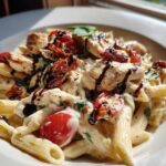 A close-up of creamy Bruschetta Chicken Pasta featuring penne, chicken pieces, cherry tomatoes, and a balsamic drizzle.