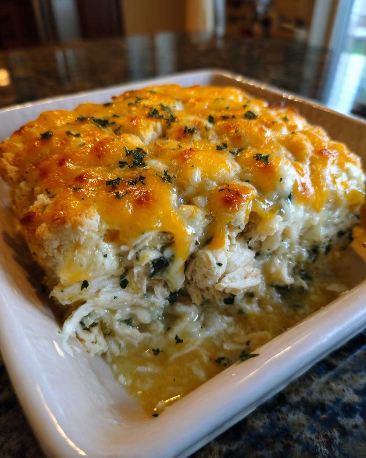 A close-up of a portion of Creamy Chicken and Spinach Casserole topped with melted cheddar cheese and parsley.