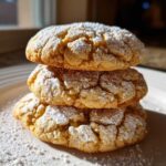 Three stacked Maple Brown Sugar Cookies dusted heavily with powdered sugar on a white plate.