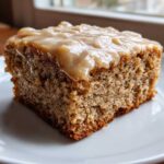 Close-up of a square slice of Moist Banana Bars with Browned Butter Vanilla Glaze on a white plate.