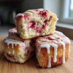A stack of three Strawberry Cheesecake Sweet Rolls, one cut open to show the berry filling, drizzled with white icing.