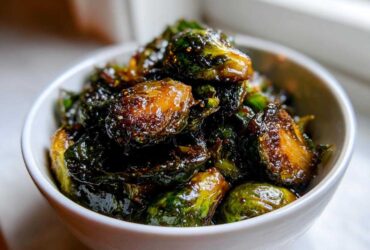 Close-up of perfectly caramelized and glazed Yard House Brussels Sprouts served in a small white bowl.